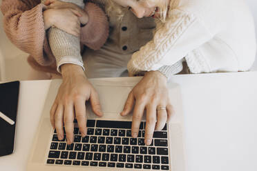 Hände eines Geschäftsmannes, der inmitten seiner Töchter zu Hause auf einem Laptop tippt - SIF00103