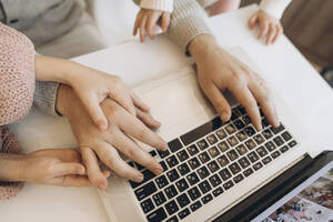 Hands of businessman working on laptop with daughters - SIF00104