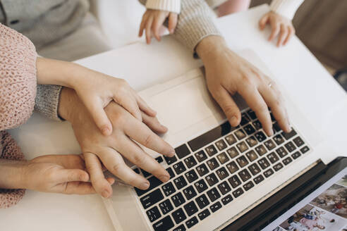 Hands of businessman working on laptop with daughters - SIF00104