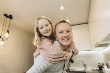 Vater nimmt seine Tochter zu Hause in der Küche huckepack - SIF00108