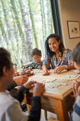 Glückliche Familie spielt Scrabble am Esstisch - CAIF32402