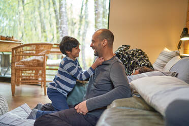 Happy father and son face to face in living room - CAIF32403