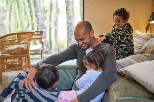 Happy father and kids playing in living room - CAIF32405