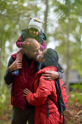 Zärtliches Paar mit kleiner Tochter küsst sich beim Wandern - CAIF32430