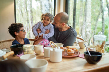 Glücklicher Vater und Kinder beim Essen am Esstisch - CAIF32431