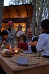 Familie isst am Tisch vor der Hütte - CAIF32438