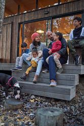 Family talking and relaxing on cabin patio - CAIF32442