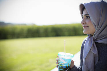 Young woman in headscarf drinking juice - CAIF32452