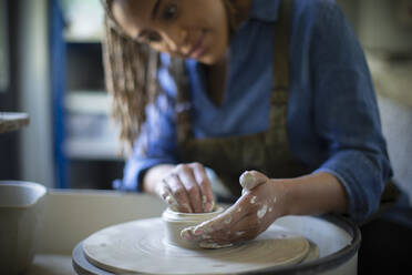 Young woman at pottery wheel in art studio - CAIF32465