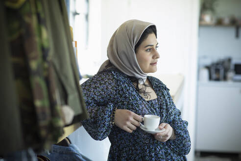Nachdenkliche junge Muslimin im Hidschab trinkt Kaffee - CAIF32476