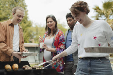 Fröhliche Freunde beim Grillen auf der Veranda - CAIF32480