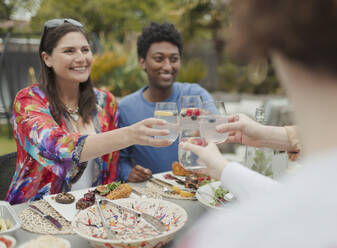 Glückliche Paare stoßen beim Mittagessen im Innenhof an - CAIF32486