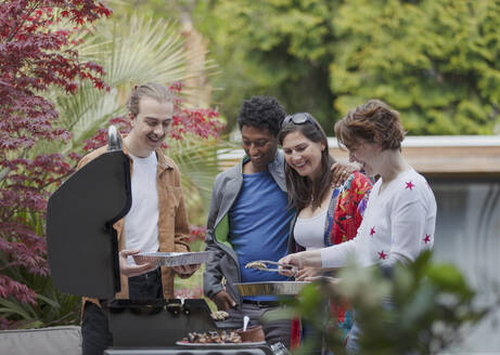 Glückliches befreundetes Paar am Grill auf der Terrasse - CAIF32493