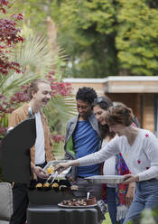 Happy friends barbecuing at barbecue grill on patio - CAIF32504