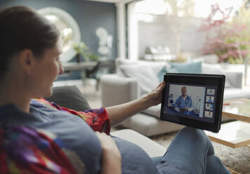 Schwangere Frau im Video-Chat mit Arzt auf digitalem Tablet - CAIF32506