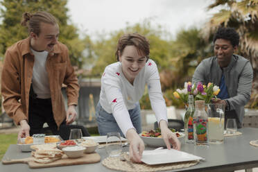 Freunde decken den Terrassentisch für das Mittagessen - CAIF32516