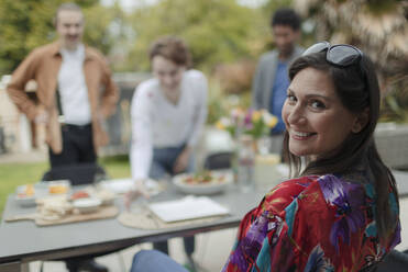 Porträt einer glücklichen Frau, die ihr Mittagessen mit Freunden am Terrassentisch genießt - CAIF32524