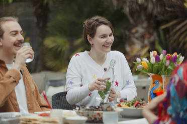 Happy young couple enjoying lunch at patio table - CAIF32527