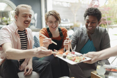 Happy friends sharing sushi lunch - CAIF32534