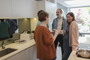 Couple friends talking and drinking tea in kitchen - CAIF32536