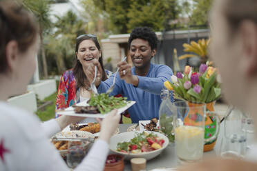 Freunde genießen ein vegetarisches Mittagessen am Terrassentisch - CAIF32540