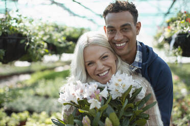 Portrait glückliches Paar mit Blumen im Gartengeschäft - CAIF32551