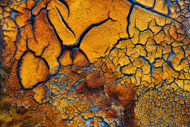 Full frame abstract background of textured earth with dried ground and various blue cracks creating patterns on orange surface - ADSF34705