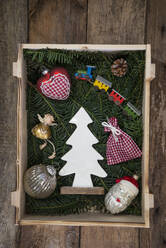 Christmas decorations lying inside crate filled with conifer twigs - LBF03636