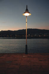 Illuminated street light by sea at dusk - MRRF02100