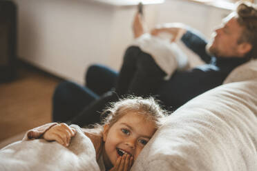 Lächelndes süßes Mädchen sitzt bei ihrem Vater auf dem Sofa - JOSEF09484