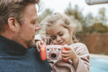 Vater mit Tochter spielt mit Spielzeugkamera - JOSEF09518
