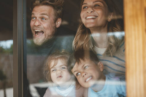 Parents and children pressing faces on window glass - JOSEF09538