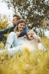 Smiling mother and father with daughter in meadow - JOSEF09548