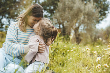 Happy mother and daughter rubbing noses in meadow - JOSEF09553