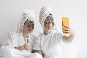 Glückliche Freunde mit Gesichtsmasken, die ein Selfie mit ihrem Handy machen - SSGF00948