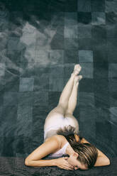 Junge Frau lehnt sich an den Rand eines Schwimmbeckens - JUBF00376