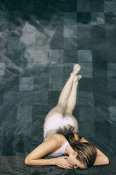 Young woman leaning on edge of swimming pool - JUBF00376