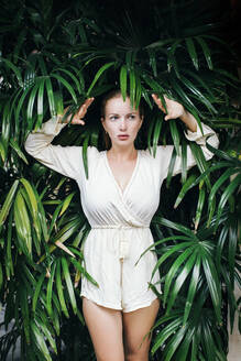 Portrait of young beautiful woman posing amid tropical plants - JUBF00379