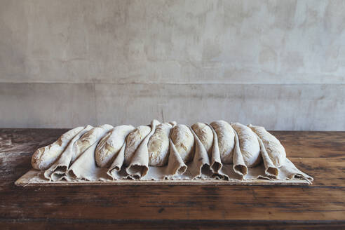 Baguette dough arranged on table in bakery - JUBF00405