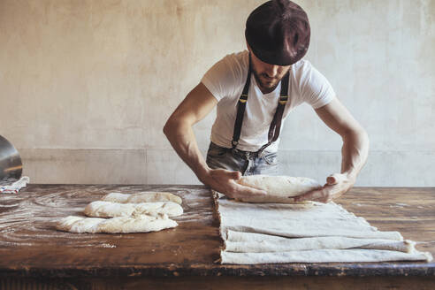 Baker arranging dough on napkin in bakery - JUBF00409