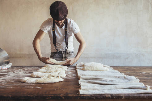 Baker arranging dough on napkin for proofing in bakery - JUBF00410