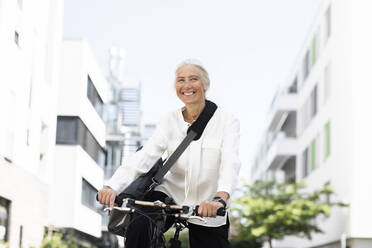 Fröhliche reife Geschäftsfrau beim Pendeln mit dem Fahrrad - SGF02912