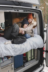 Smiling woman hugging friend sitting in motor home - MRRF02107