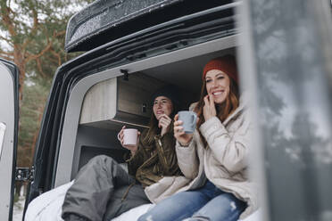 Lächelnde Frauen, die im Wohnmobil zusammensitzen und Kaffee trinken - MRRF02108