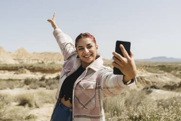 Glückliche Frau nimmt Selfie durch Handy auf sonnigen Tag - JCCMF06268