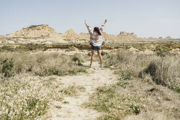 Woman standing with arms raised enjoying sunny day - JCCMF06269