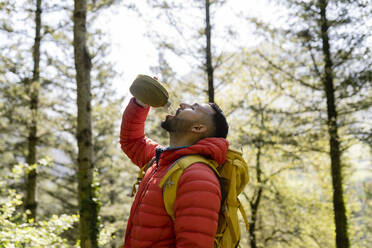 Mann trinkt stehend im Wald Wasser - JCCMF06280