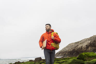 Mann mit Rucksack und Laptop an der Küste - JCCMF06316