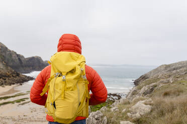 Mann mit gelbem Rucksack schaut auf Aussicht - JCCMF06328