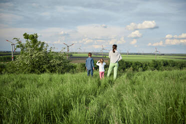 Mutter mit Sohn und Tochter betrachten die Windräder auf dem Feld - ZEDF04538